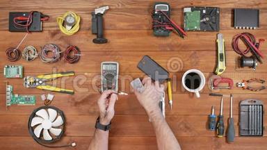人修手机.. 检查设备内部的部件。 木桌顶景..